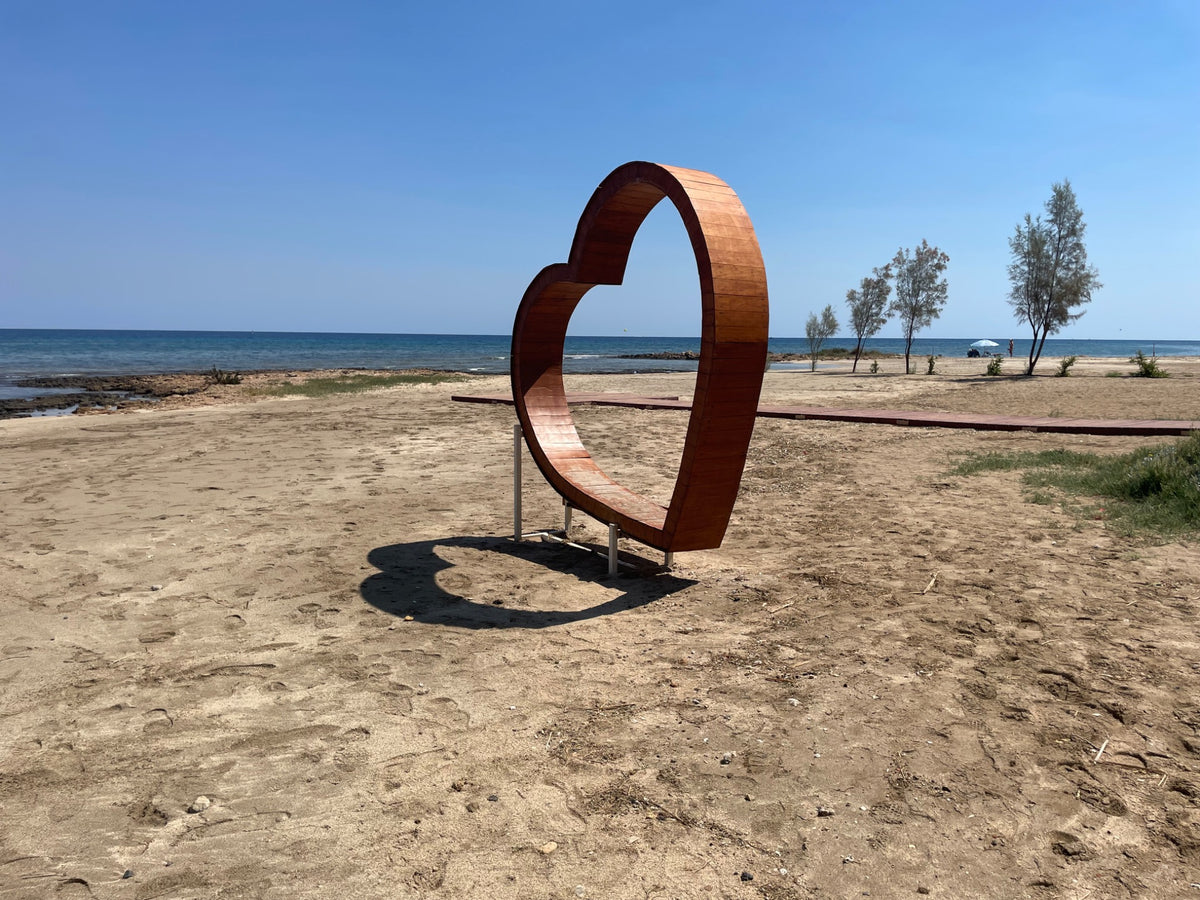 Wooden heart sculpture on a peaceful sandy beach beside the sea