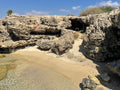 Secluded sandy cove surrounded by rugged coastal rocks and clear water