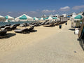 Peaceful sandy beach with sun loungers and turquoise parasols